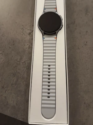 Galaxy Watch 7 - Säljer en Samsung Galaxy Watch7. Den kommer i sin originalförpackning. Jag fick den i present, har öppnat den men tyvärr aldrig använt den eftersom det inte går att koppla den till iPhone.