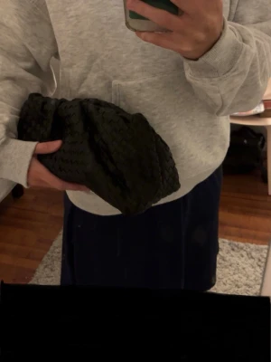 Svart flätad kuvertväska i skinn - Säljer en svart kuvertväska med snygg flätad väska. Perfekt storlek för att få plats med det viktigaste och enkel att bära i handen.