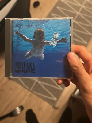 Nirvana nevermind cd - Bilderna visar ett Nirvana Nevermind CD-album och ingen väst finns med på någon av bilderna. Vänligen ladda upp bilder på västen om du vill ha en beskrivning.