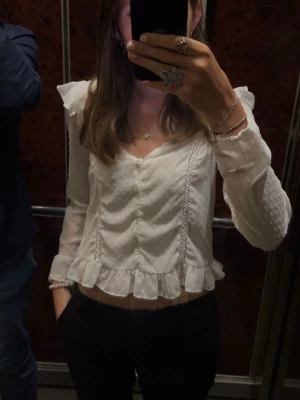 Vit blus - En vit blus från Zara, med volanger vid axlarna och längst nere. Säljer då den inte kommer till användning längre. Det är ett band till en av knapparna som har gått upp lite men den är lätt att sy fast igen. Storlek XS💗