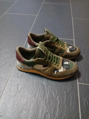 Valentino Rockrunner sneakers camouflage - Säljer ett par Valentino Rockrunner sneakers med grön, brun och beige camouflage-mönster. Har lite "slip" märken, fråga gärna om bild om du vill se mer ordentligt. Storlek 40 men passar även 41.