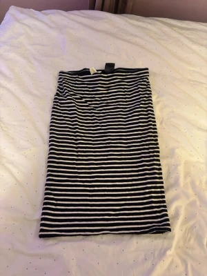 Randig svartvit kjol från H&M - Säljer en svartvit, midilång kjol från H&M BASIC i storlek S. Kjolen har horisontella ränder och är gjord i mjuk bomull, perfekt för en chill och enkel look. Passar dig som gillar klassiska mönster och enkel stil.