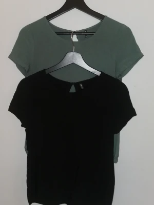 Två jättefina toppar från ONLY, storlek XS - Två jättefina toppar/t-shirts från Only. Båda har en liten öppning med knapp i nacken. Lite lösare modell. Ena är grön och den andra är svart. Båda inköpta på vero moda.  Är i mycket fint skick. Materialet är mjukt och lätt, perfekt till jeans eller kjol. Storlek XS (34)