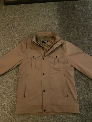 Beige parkajacka från J.Lindeberg - Säljer en beige parkajacka från J.Lindeberg i storlek S. Inga skador och använd ett fåtal gånger. Mitt pris 1750 kr, skriv vid minsta fråga!⭐️