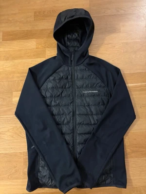 Svart pufferjacka Peak Performance - Säljer en svart cardigan/jacka från Peak Performance i storlek L. Men passar även M.                        Perfect för hösten våren eller vintern och den har en clean, sportig look. Jackan är i mycket bra skick och inte använd så mycket. Nypris låg på 2399. Först till kvarn.
