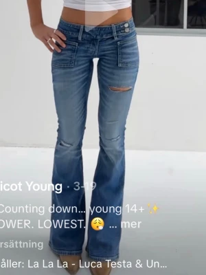 Blå bootcut jeans med slitningar - Säljer ett par blå bootcut jeans från Gina Tricot med låg midja och slitna detaljer på låret och knäet. Jeansen har dubbla knappar i midjan. Använt fåtal gånger💕
