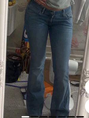 Ljusblå bootcut jeans - Säljer ett par ljusblå jeans med bootcut-modell. Pepe jeans från London, nypris 1075kr. Jeansen har klassisk femficksdesign, normal midja och är tillverkade i mjukt denimtyg. Perfekta för dig som gillar en retroinspirerad look och vill ha ett par jeans som sitter snyggt över höfterna och släpper ut vid benen. ( Storlk: 25/32 ) Midja/längd 