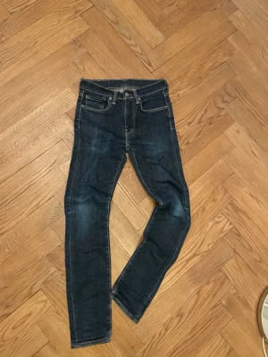 Levi's 511 mörkblå jeans W28 L32 - Säljer ett par Levi's 511 jeans i mörkblå tvätt med klassiska fem fickor och snygga kontrastsömmar. Tillverkade i slitstarkt jeansmaterial, perfekta till sneakers eller boots.