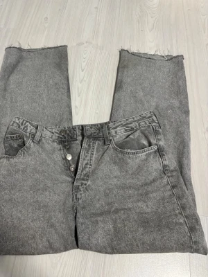 Grå jeans från H&M - Grå tvättade jeans. Klassisk fick modell med knappgylf och bälteshällor. Jeansen har en cool vintagekänsla och är perfekta för en avslappnad streetstil.