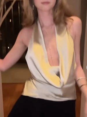 Champagnefärgad halterneck topp i satin - Säljer en champagnefärgad halterneck topp i glansigt satinmaterial. Toppen har djup urringning och draperad framsida som ger en snygg siluett. Den är ärmlös och knyts i nacken för en justerbar passform. Perfekt för dig som gillar trendiga och stilrena plagg.