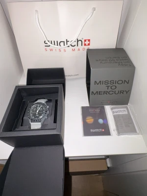 Omega x Swatch Mission to Mercury - Säljer en stilren Omega x Swatch Mission to Mercury från MoonSwatch-kollektionen. Klockan har svart urtavla med kronograffunktion, tachymeter och grått band med Omega-logga. Kommer i originalbox med tillbehör och manual.