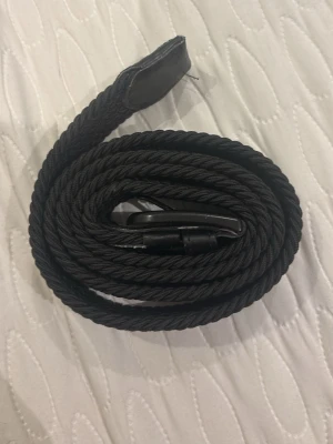 Svart flätad bälte från Jack and Jones  - Säljer ett svart flätat bälte från Jack and Jones . Bältet har en snygg textilfläta och detaljer i skinn vid ändarna. Perfekt accessoar för att lyfta vilken outfit som helst.