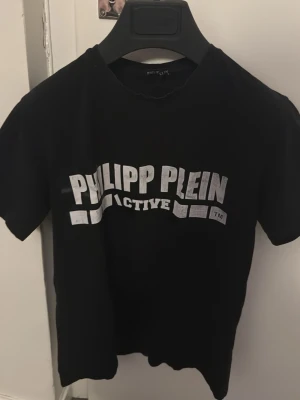 Svart Philipp Plein Active t-shirt - Snygg svart t-shirt från Philipp Plein Active med vit logga tryckt framtill och längs ryggen. Klassisk rund hals och korta ärmar. Perfekt för dig som gillar streetwear och vill ha en statement-tee med cool design.