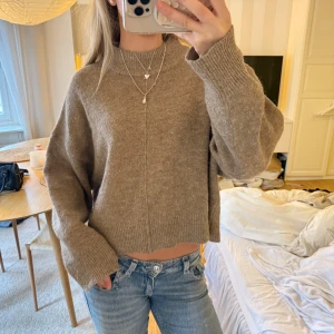 Beige stickad tröja från Gina tricot  - Supermysig beige stickad tröja från Gina tricot med rak passform och ribbade muddar. Tröjan har en högre hals och är långärmad, alpacka och ull blanding 