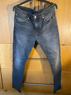 Svarta jeans från Calvin Klein - Snygga svarta jeans från Calvin Klein med diskret tvättad look. Klassisk femficksmodell med logga på myntfickan och svart läderpatch bak. Jeansen har smal passform och raka ben, perfekta till sneakers eller boots.