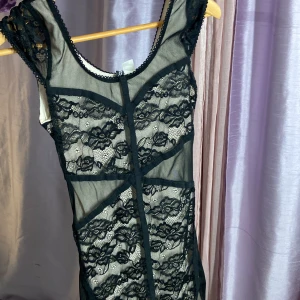 Svart spetsklänning från H&M Divided - Supersnygg kort klänning från H&M Divided i svart mesh och spets med blommigt mönster. Klänningen är figurnära med transparenta partier och rundad halsringning. Perfekt för dig som vill sticka ut med en edgy och trendig look.jätte fin bra skick,har en till som är beige ochså om man är tvillingar.stretch passar 34-38