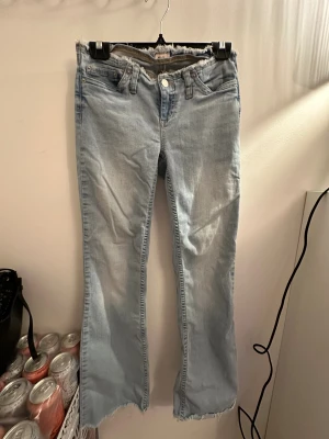 Ljusblå bootcut jeans från Nelly - Snygga ljusblå jeans från Nelly med bootcut passform och fransiga kanter både vid midjan och bensluten. Klassisk femficksmodell med knapp och dragkedja framtill. Perfekta för dig som gillar en avslappnad och trendig look.
