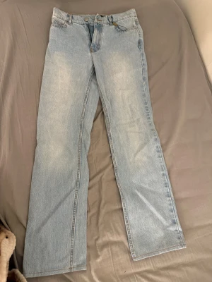 Ljusblå raka jeans - Snygga ljusblå jeans med klassisk rak passform och fem fickor. Jeansen har en enkel design med knapp och dragkedja framtill, samt bälteshällor. Perfekta för dig som gillar en clean och avslappnad stil.