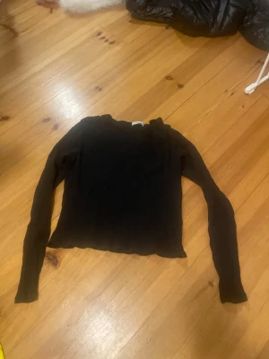 Svart ribbad långärmad tröja Lindex - Svart långärmad tröja från Lindex med ribbad struktur och rund hals. Tröjan har en enkel och clean look, perfekt att matcha med jeans eller kjol. Materialet är mjukt och stretchigt för en skön passform.