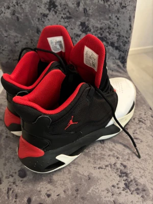 Nike Air Jordan Flight svart/röd/vit - Säljer ett par Nike Air Jordan Flight sneakers i svart, rött och vitt. Skorna har klassisk Jordan-logga på sidan, röd meshfoder och texten 'Flight' broderad på plösen. Ovandelen är i syntet och skinn med snörning och rund tå. Perfekta för dig som gillar streetstyle.