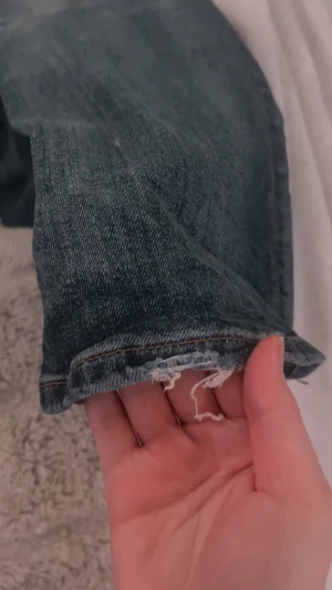 Blå bootcut jeans från Bershka - Snygga blå jeans från Bershka med bootcut passform. Jeansen är low waist I midjan och är Färgen är ljusblå med diskreta slitningar och tvättade detaljer längs benen. Använd fåtals gånger men är långa på mig o då har fått slitningar 
