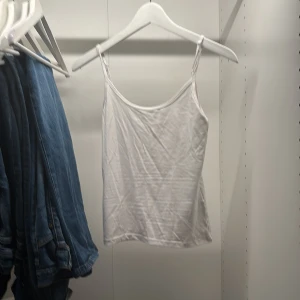 Vit linnetopp från Gina Tricot XS - En enkel och stilren vit linnetopp från Gina Tricot, Elevated Basics-kollektionen. Toppen har tunna axelband och rak passform, perfekt att matcha med jeans eller kjol. Gjord i mjuk bomull för en skön känsla.