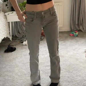 Grå raka jeans med låg midja - Snygga grå jeans med låg midja och utsvängda. Klassisk femficksmodell med knapp- och dragkedjestängning. Perfekta till en avslappnad stil och lätta att matcha med det mesta. Materialet är mjukt och skönt jeans.