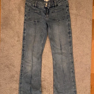 Blå bootcut jeans från Gina Tricot - Snygga blå jeans från Gina Tricot med bootcut passform och låg midja. Jeansen har två stora framfickor, dubbla knappar och synliga sömmar längs benen. 💕💕💕