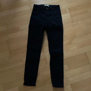 Svarta Molly jeans från Gina Tricot - Svarta Molly jeans från Gina Tricot. Jeansen har hög midja och är tillverkade i stretchigt bomullsmaterial för en bekväm passform. Perfekta för dig som gillar en stilren och enkel look.