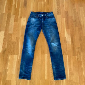 Blå jeans från Scotch & Soda modell Ralston - Snygga blå jeans från Scotch & Soda med coola slitningar framtill. Jeansen är av modellen Ralston. Köptes nya använda 2 gånger.  Midja 30 längd 32. Ny pris 1400