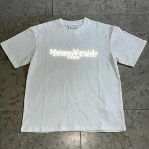 Vit Maison Margiela t-shirt - Vit t-shirt från Maison Margiela i storlek S med tryckt logga och text på bröstet samt siffror på ryggen. Skick 10/10 och fraktar inom 24h✅
