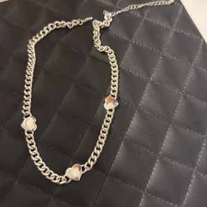 Silverfärgat halsband med hjärtan - Kedjehalsband i silverfärg med tre små hjärtan som detaljer. Snygg och trendig accessoar som passar perfekt till att lyfta vilken outfit som helst. Justerbar längd med karbinlås. EJ ÄKTA SILVER, Köparen står för frakt :)