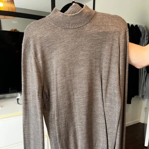 Beige polotröja i tunn ull - Snygg beige polotröja i tunn och mjuk ull. Tröjan har lång ärm och en klassisk ribbad polokrage som ger en clean och stilren look. 