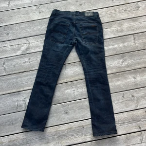 Nudie Jeans - Riktigt snygga Nudie Jeans i mörkblå! Skick 9/10, knappt spår av användning förutom ytterst lite på läderlappen. Storleken är 32/32 och modell syns på bild. Hör av er vid frågor eller funderingar 🙏