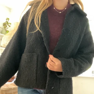 Svart kappa - Snygg svart jacka i ull med rak passform och stora knappar framtill. Jackan har två stora fickor och klassisk krage. Perfekt för dig som gillar en stilren look med lite struktur i materialet. Storleken står inte men passar mig som bär XS!💗🥰