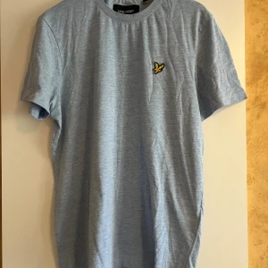 Ljusblå t-shirt från Lyle & Scott - Säljer en riktigt snygg ljusblå t-shirt från Lyle & Scott med klassisk passform och korta ärmar. T-shirten är i storlek S och är i bra skick!