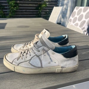 Philippe Model vita sneakers med svarta detaljer - Säljer ett par vita Philippe Model sneakers med svarta detaljer på hälen och ljusblå insida. Skorna säljs i befintliga skick, storlek 41.  Bara att skriva vid frågor eller funderingar, pris kan diskuteras vid snabbare affär bara att komma med prisförslag!😇