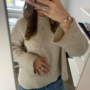 Beige stickad tröja från Gina Tricot - Mysig beige stickad tröja från Gina Tricot med breda ribbade muddar och avslappnad passform. Perfekt för lager-på-lager och har en klassisk rund halsringning. Snygg till både jeans och kjol. Sitter som en S