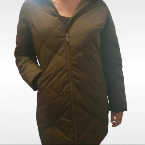 Quiltad mörkgrön pufferjacka Five Seasons - Säljer en lång, quiltad pufferjacka från Five Seasons i mörkgrönt. Jackan har dragkedja framtill, två sidofickor med dragkedja och ett snyggt märke på ärmen. Insidan är fodrad med mjuk fleece för extra värme. Perfekt för kalla dagar.