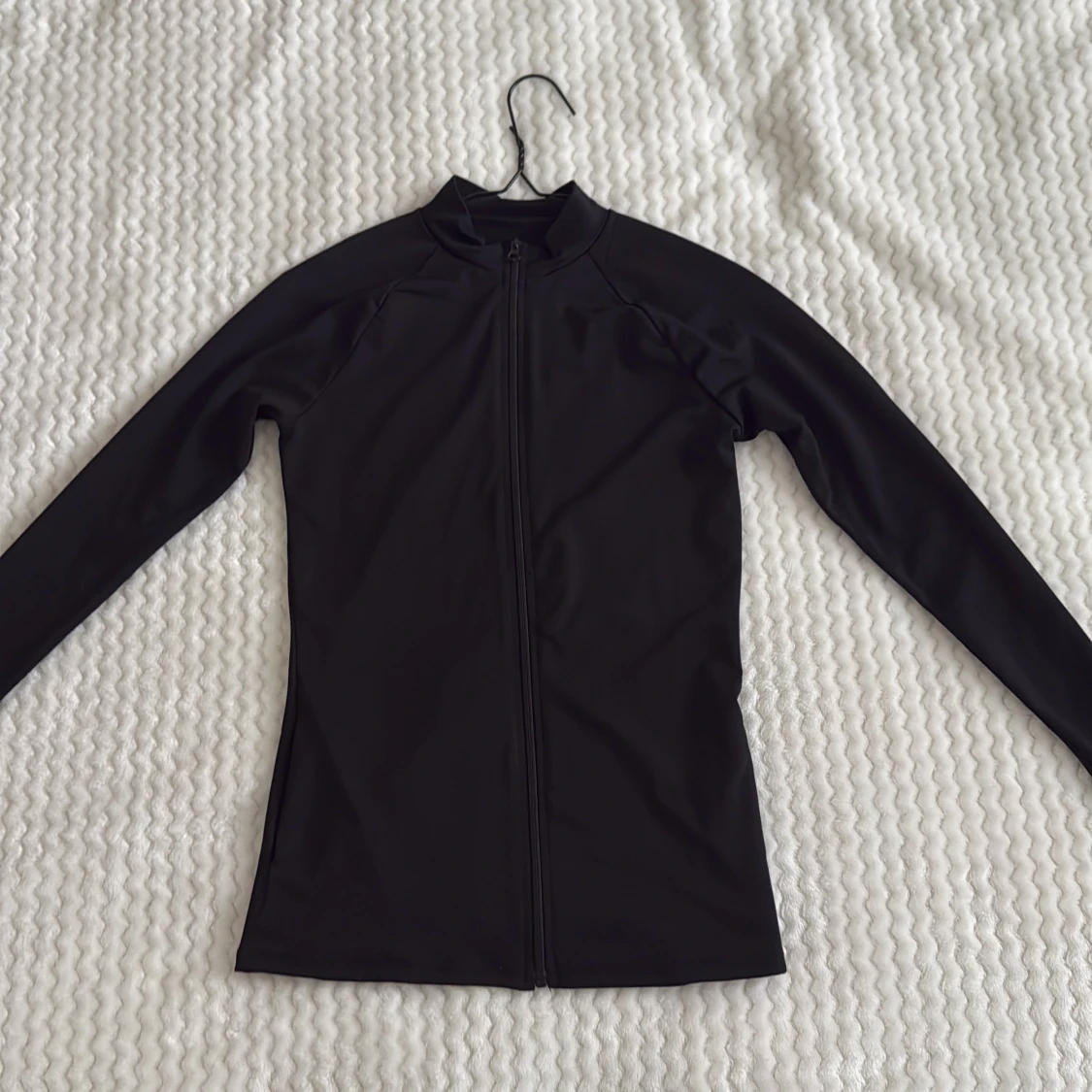 Svart ziptröja i syntetmaterial