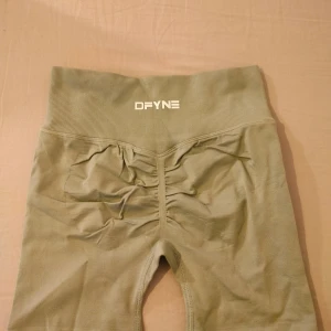 Gröna DFYNE shorts med scrunch - Snygga gröna shorts från DFYNE i storlek S, med hög midja och scrunch-detalj bak för extra shaping. Materialet är mjukt och stretchigt, tillverkat av 90% polyamid och 10% elastan. Perfekta för gymmet eller andra träningspass.