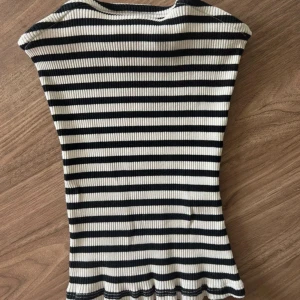 Randig ribbad tubtopp från NA-KD XS - Säljer en svartvit randig tubtopp från NA-KD i storlek XS. Toppen är ribbad och har bandeau-modell med stretchigt material som sitter tight mot kroppen. Perfekt att styla med höga jeans eller kjol för en trendig look.