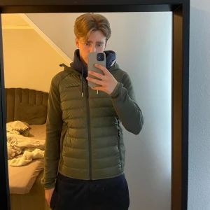  hybridjacka från Peak Performance - Säljer en olivgrön hybridjacka från Peak Performance med huva. Jackan har quiltade partier fram och bak, släta ärmar och sidor samt två dragkedjefickor. Perfekt till de kallare tiderna. Helt ny använd max 5 gånger men den blev förliten. passar bäst till XS men också S. priset går självklart att diskutera.