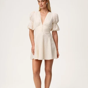 Helt ny Adoore sicily mini dress strl 34 light creme - Superfin kort klänning i champagnefärg med puffiga kortärmar och djup v-ringning. Klänningen har knappar framtill och markerad midja som ger en snygg siluett. Perfekt för sommarens alla tillfällen, med lätt och luftig känsla. Helt ny med tags! Nypris: 1495kr, passa på!