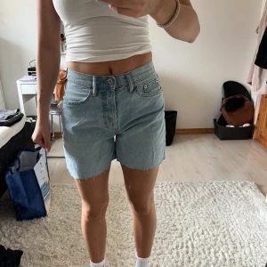 Ljusblå jeansshots - Säljer ett par ljusblå jeansshorts. Shortsen har hög midja och kan bäras både med upprullad eller nedvikt fåll. Från lager 157