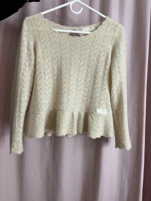 Beige stickad tröja Odd Molly - Supersöt beige stickad tröja från Odd Molly med volang nertill och diskret mönsterstickning. Jätte skönt material som känns bra mot huden.Tröjan har rund halsringning och långa ärmar, perfekt för lager-på-lager och en feminin look. Står ingen storlek men passar mig som är xs men även till folk som är S.