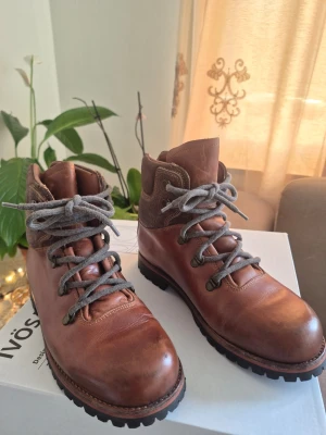 Vandringskängor / Bergskängor – Duna Running, Brun, EUR 41 mindre i storlek - Rejäla vandringskängor i äkta läder med Cortina Roccia wings-sula av hög kvalitet (Made in Italy). Stabila och slitstarka, passar bra för vandring, trekking och lättare bergsterräng.  Detaljer: Storlek: EU 41 Märke: Duna Running Sula: Cortina Roccia wings  Material: Äkta läder Skick: jättebra skick, (se bilder).  Bekväma och hållbara kängor med bra grepp. Perfekta för dig som vill ha kvalitet till ett bra pris.