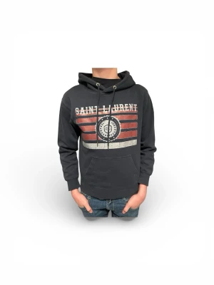 Saint Laurent Huvtröja - Säljer en snygg och sällsynt Saint Laurent hoodie. Hoodien är i nytt skick och väldigt populär. Hoodien finns inte tillgänglig i butik längre. Hoodien är perfekt nu inför våren.