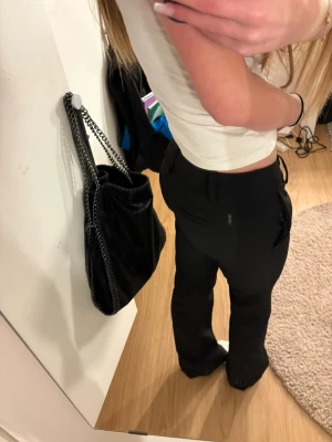 Svarta kostymbyxor med rak passform - Säljer ett par stilrena svarta kostymbyxor med rak passform och hög midja. Byxorna har klassiska fickor på sidorna och bälteshällor i midjan. Perfekta till en snygg topp eller skjorta för en clean look.