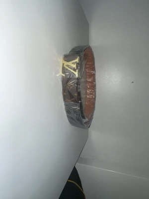 Louis Vuitto - Snyggt bälte från Louis Vuitto med klassiskt monogrammönster i brunt och guldigt L spänne. Bältet är i läder med ljusbrun insida och vita sömmar. Perfekt accessoar för att lyfta din outfit.